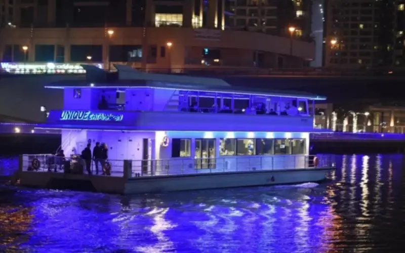 Luxury traditional wooden dhow sailing through Dubai Marina with illuminated skyscrapers in the background